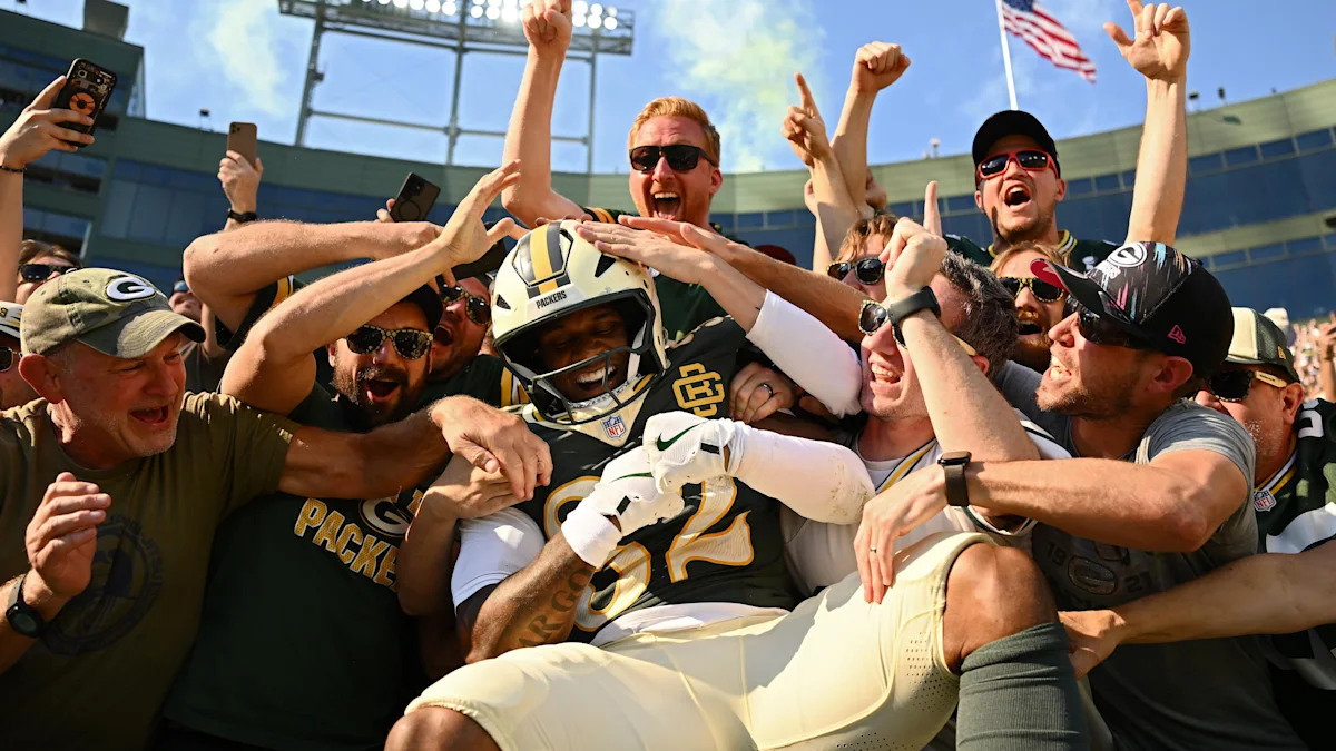 Torcedores comemoram com um jogador dos Packers em Lambeau Field.