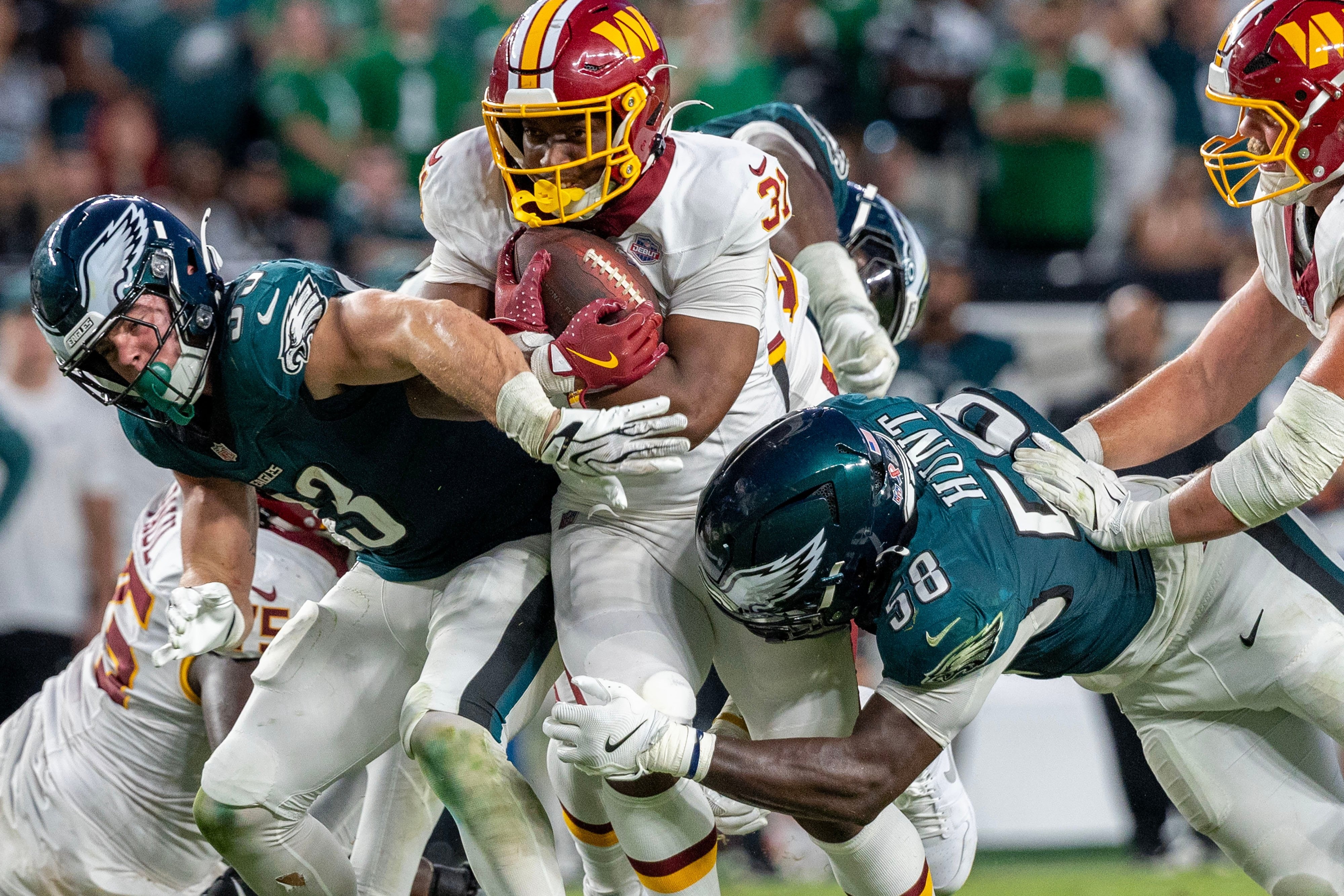 Kaytron Allen, dos Commanders, é derrubado por Jalyx Hunt, dos Eagles, em Filadélfia, em 13 de setembro de 2026.