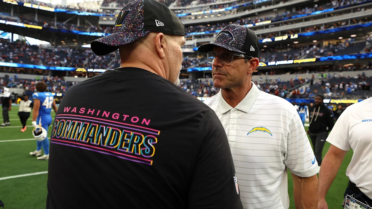 Dan Quinn e Jim Harbaugh conversam à beira do campo.