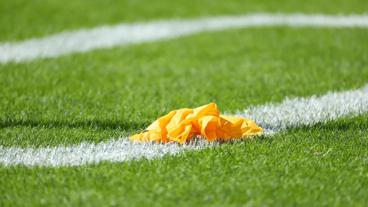 Bandeira amarela de penalidade sobre o gramado.