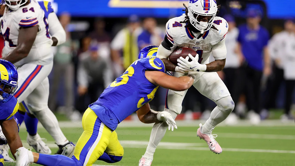 Nate Landman tenta tirar a bola de James Cook em Rams x Bills.