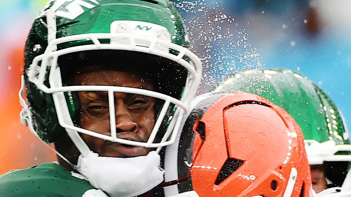 Geno Smith é atingido no capacete por Jared Verse durante Jets–Browns.