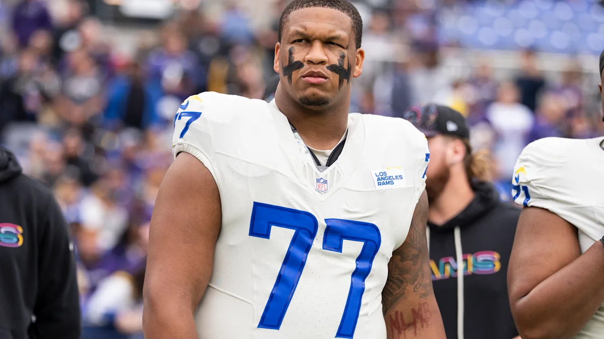 Alaric Jackson com uniforme do Los Angeles Rams; imagem ilustrativa da notícia sobre sua suspensão.