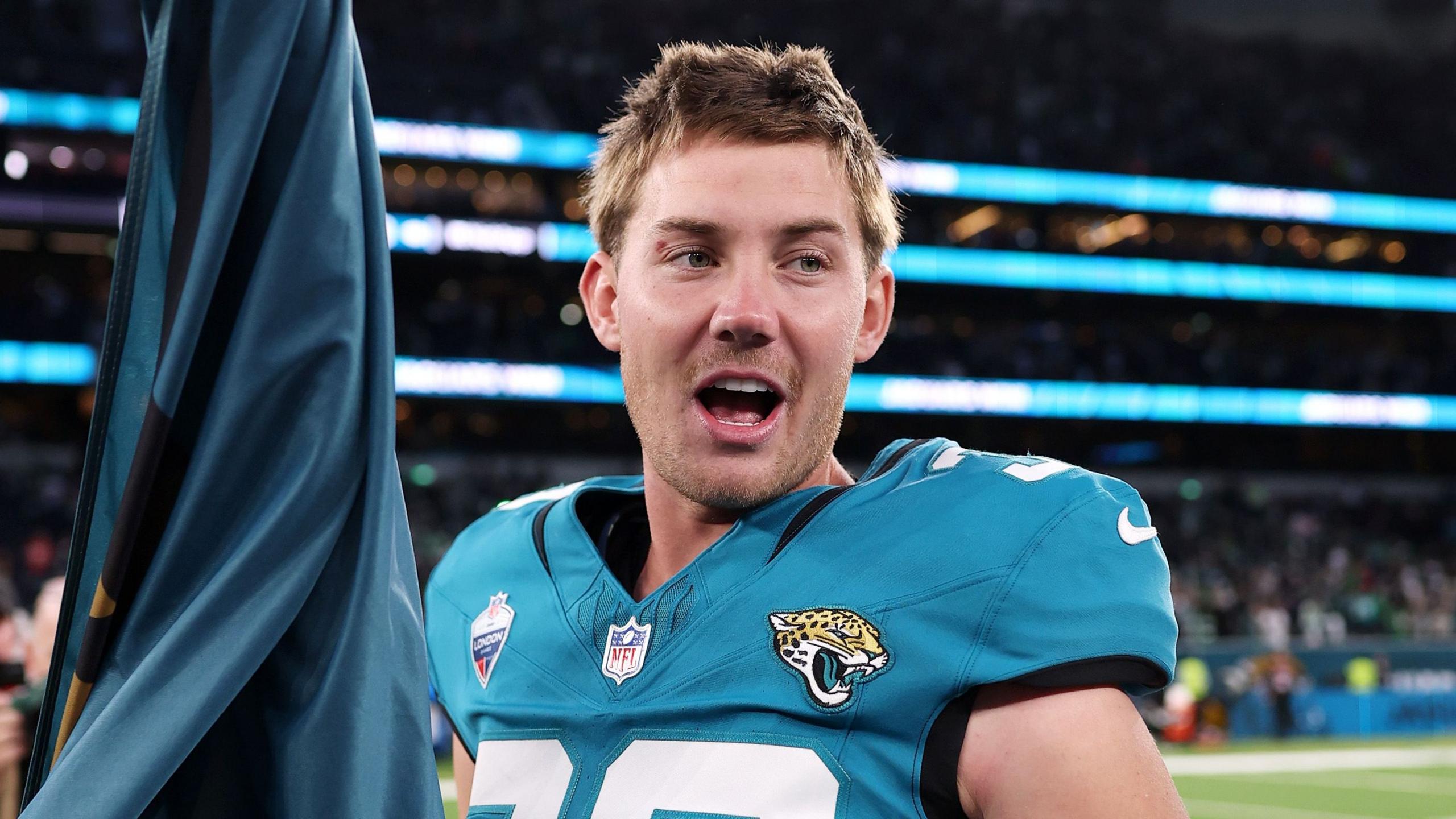 Cam Little segura uma bandeira após a vitória dos Jaguars em Londres.