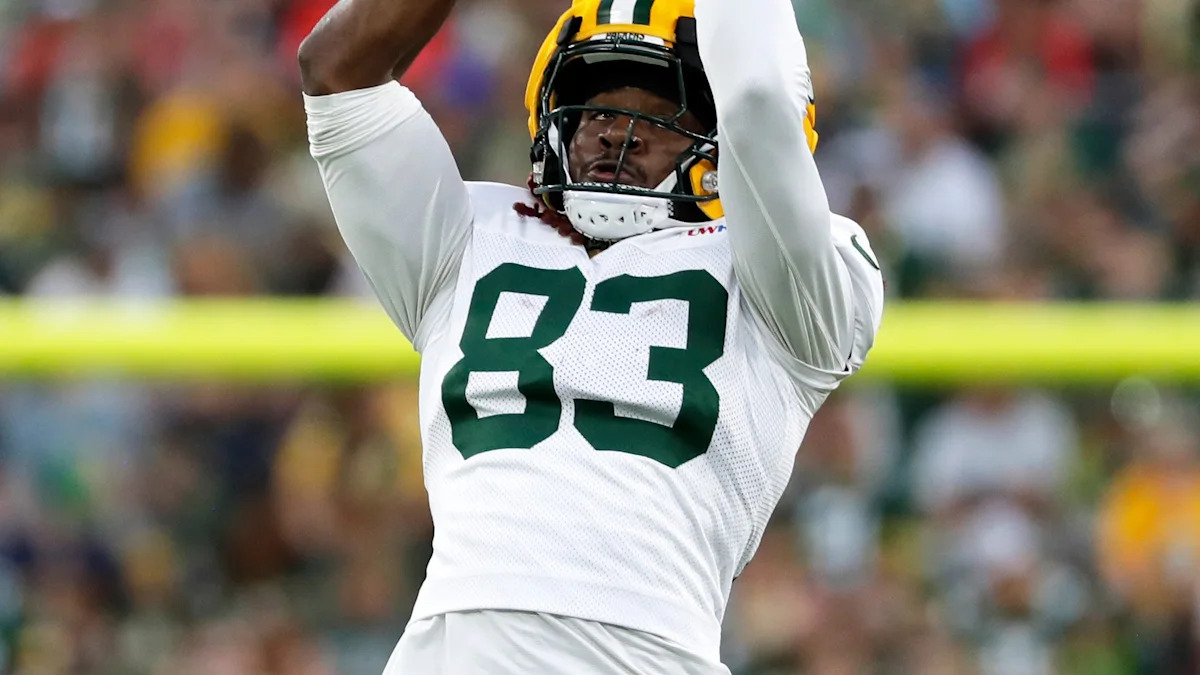 Savion Williams levanta os braços usando o uniforme dos Packers.