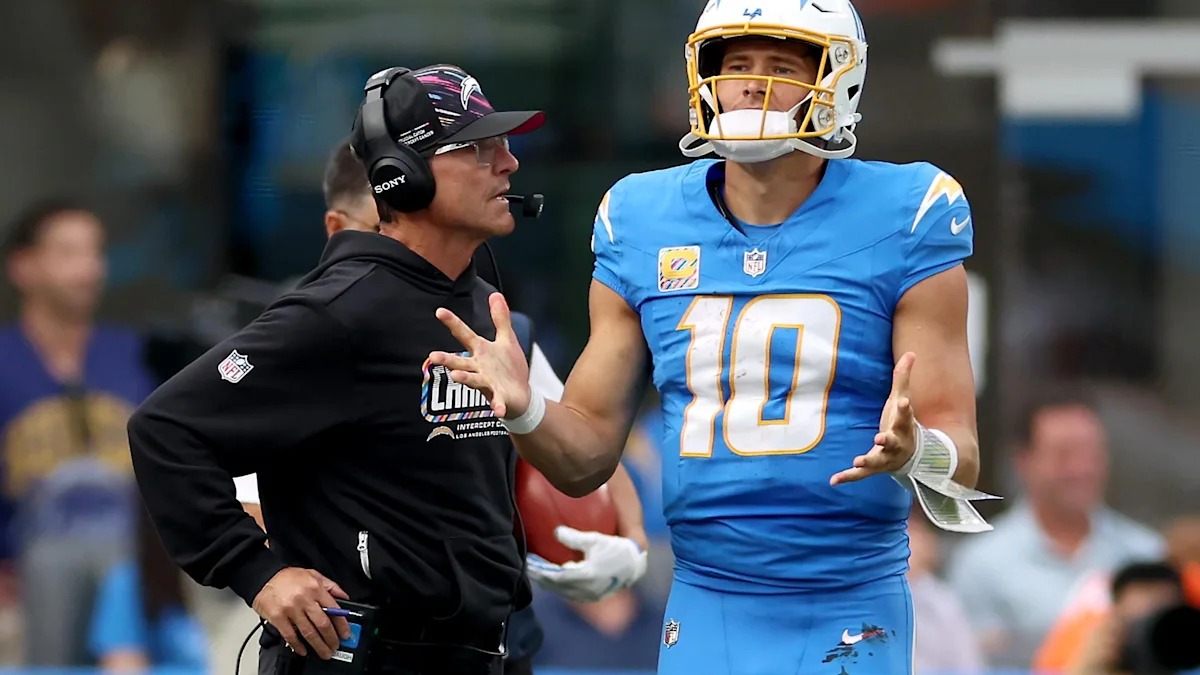 Justin Herbert conversa com um integrante da comissão dos Chargers durante o treino.