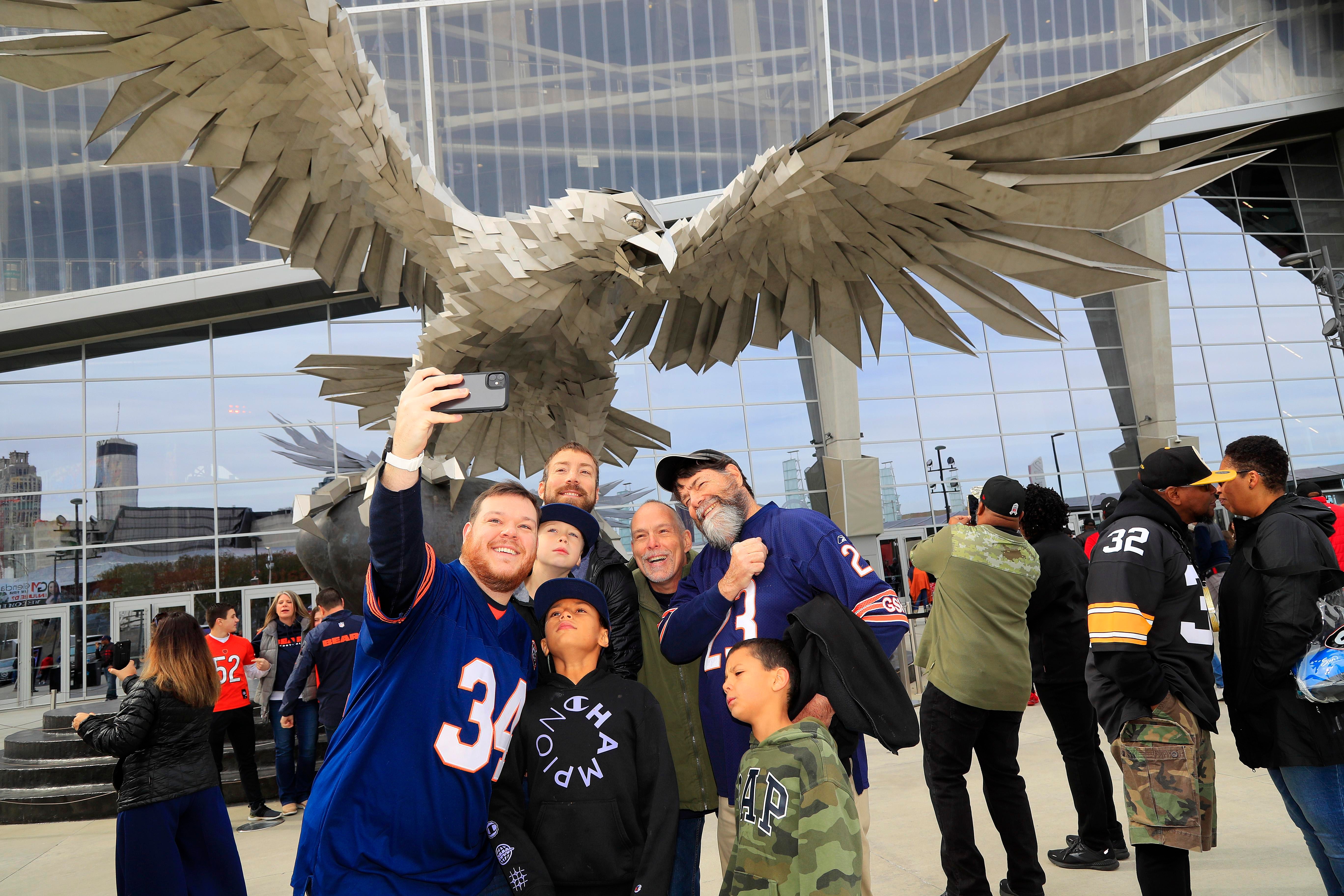 Torcedores posam diante da escultura metálica de um falcão antes de Bears x Falcons, em 20 de novembro de 2022, no Mercedes-Benz Stadium, em Atlanta.
