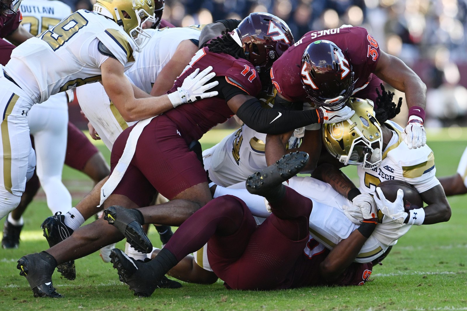 Rahkeem Smith, de Georgia Tech, é derrubado por DQ Smith, Curtis Jones Jr. e Daniel Jennings, de Virginia Tech, durante o segundo quarto, em 17 de outubro de 2026, em Blacksburg.