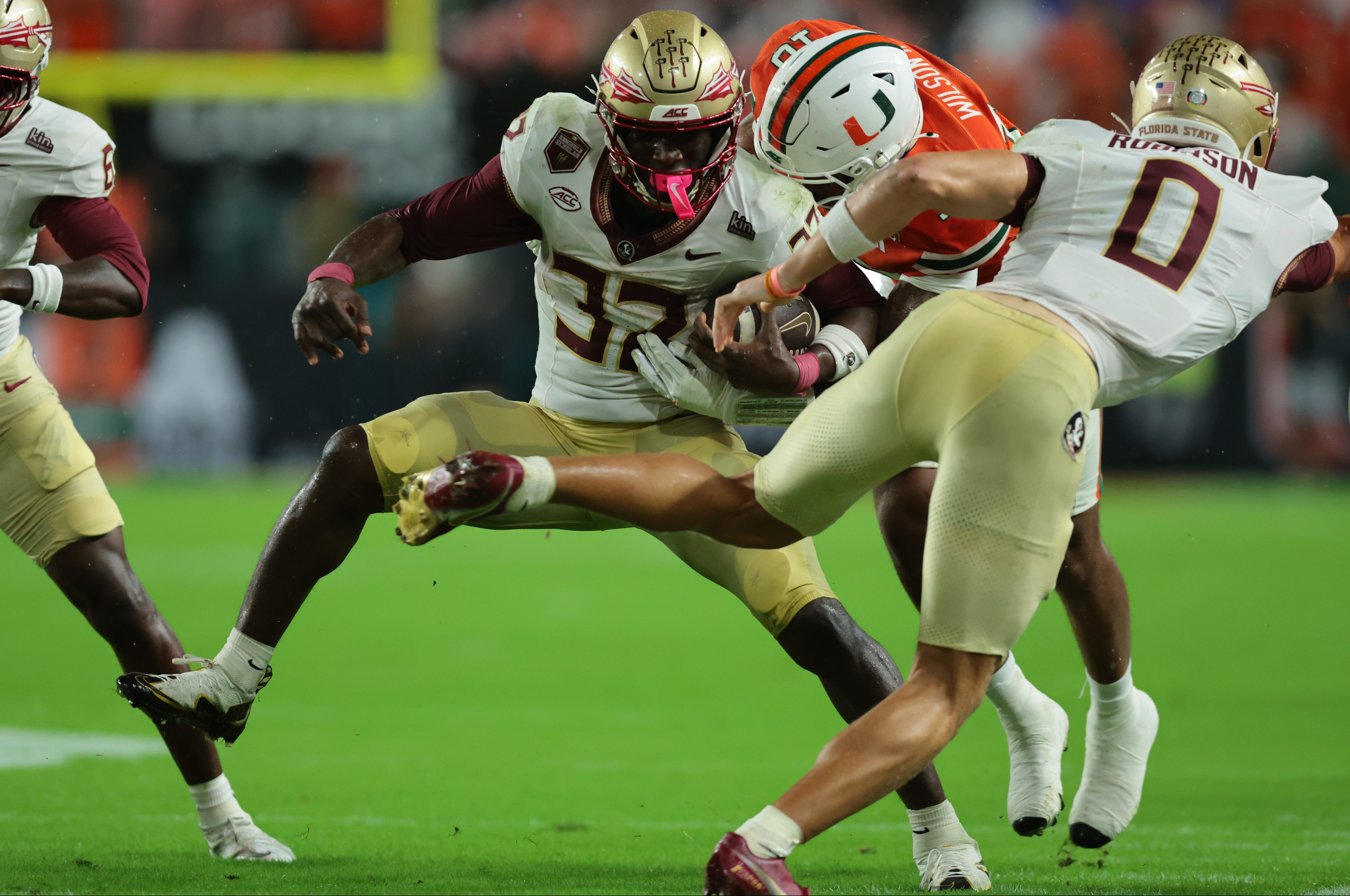 Jogador de Florida State conduz a bola em meio a defensores de Miami durante o clássico universitário.