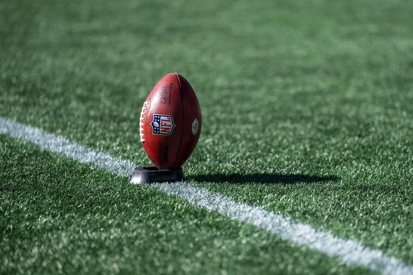 Bola de futebol americano apoiada sobre o gramado antes de uma partida da NFL.
