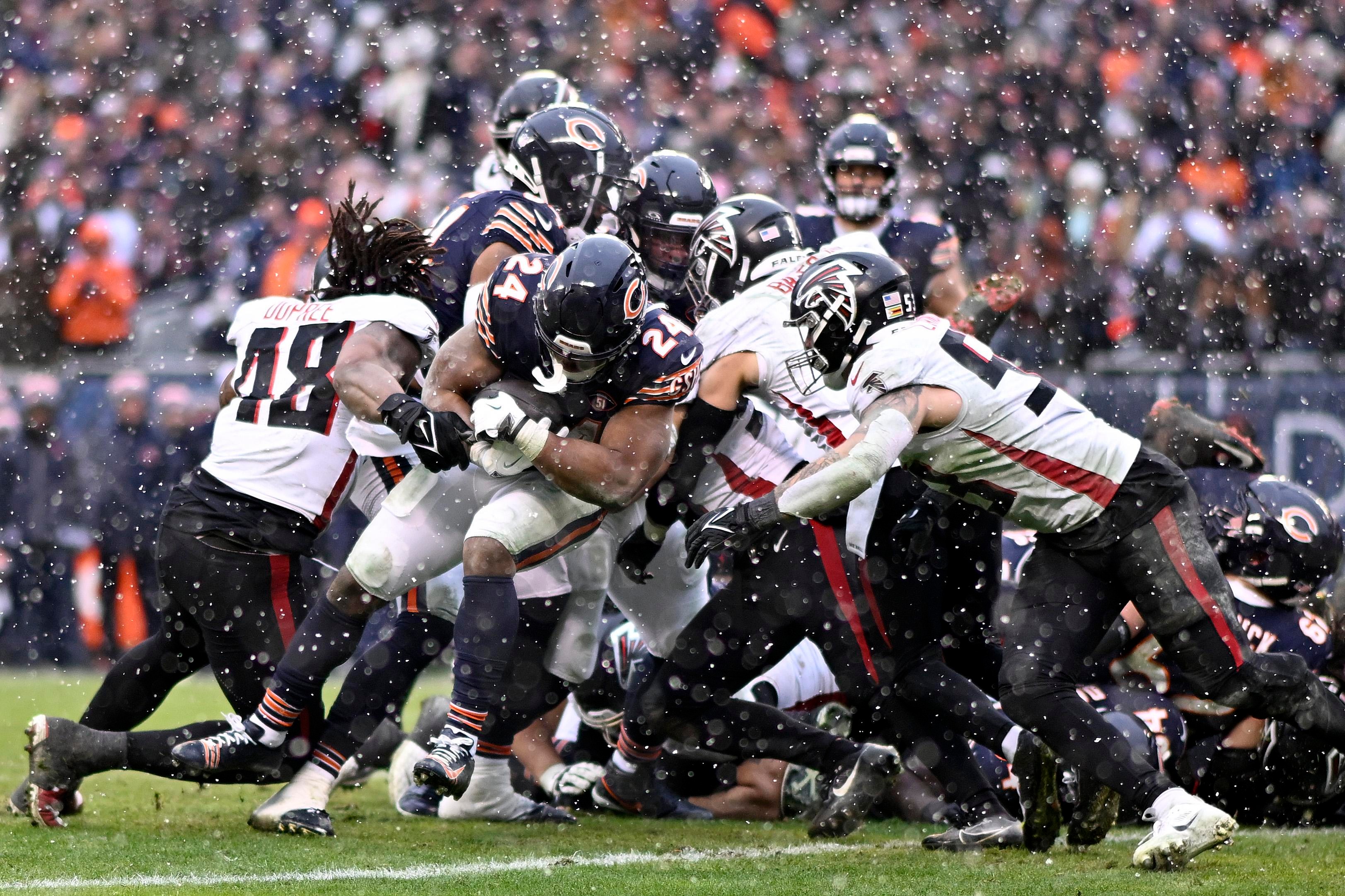 Jogadores do Chicago Bears e do Atlanta Falcons disputam uma jogada sob a chuva.