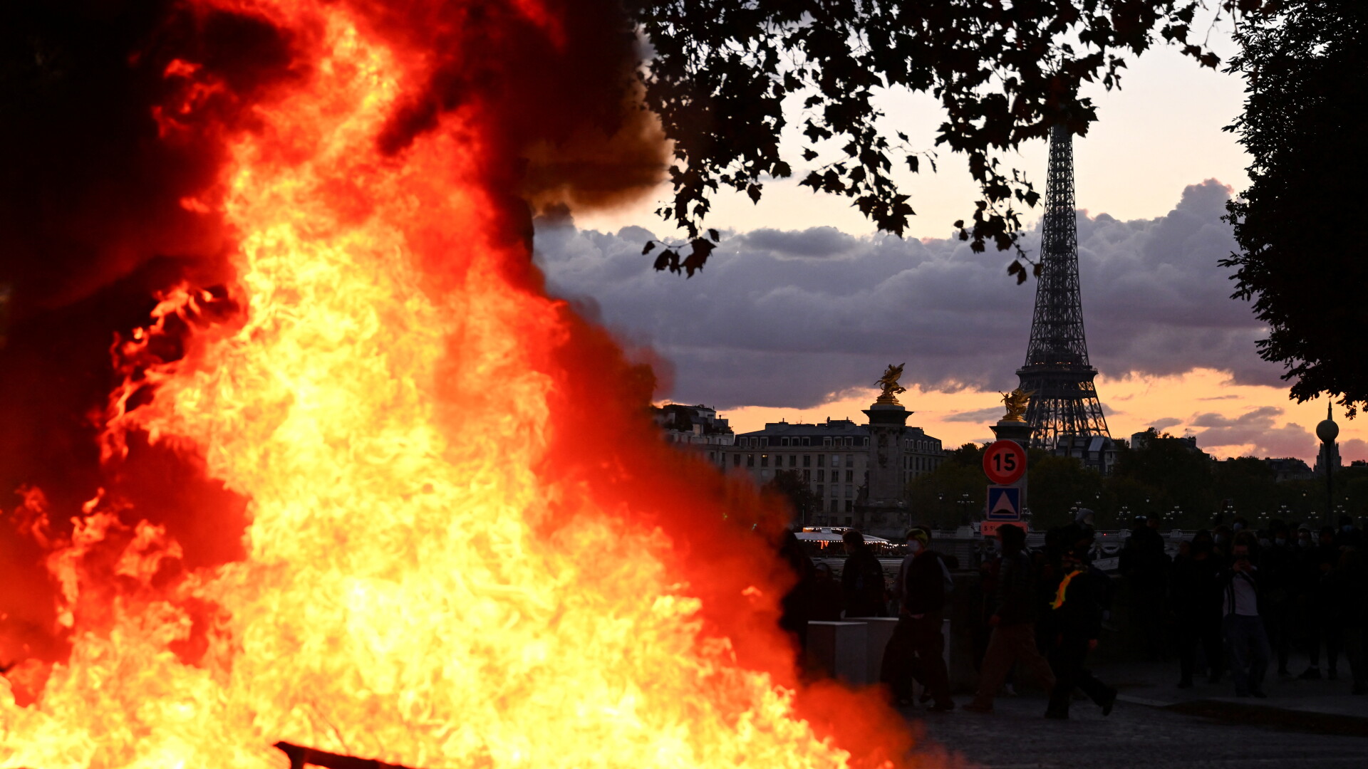Incêndio durante protesto em Paris, com a Torre Eiffel ao fundo.