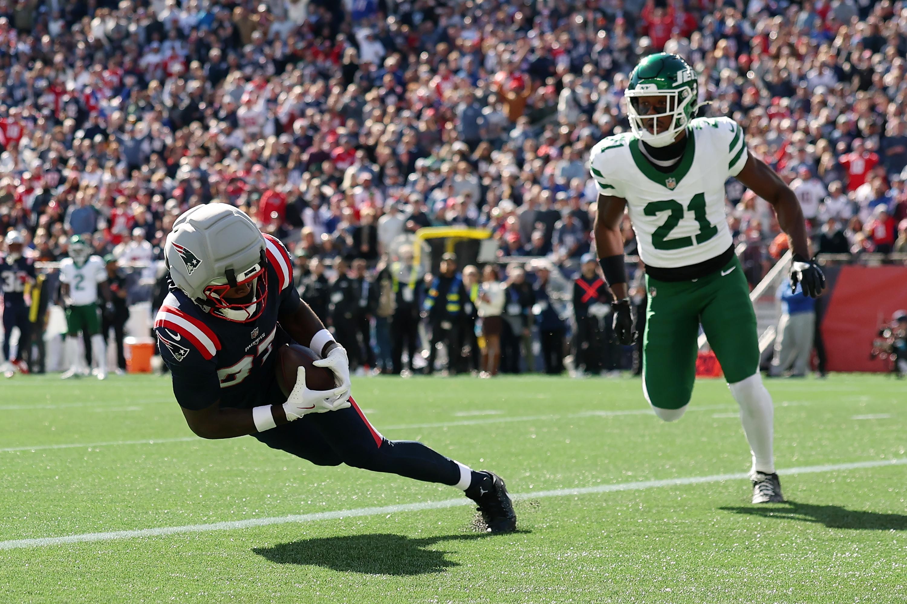 Romeo Doubs, do New England Patriots, marca um touchdown contra a cobertura de Brandon Stephens, do New York Jets.