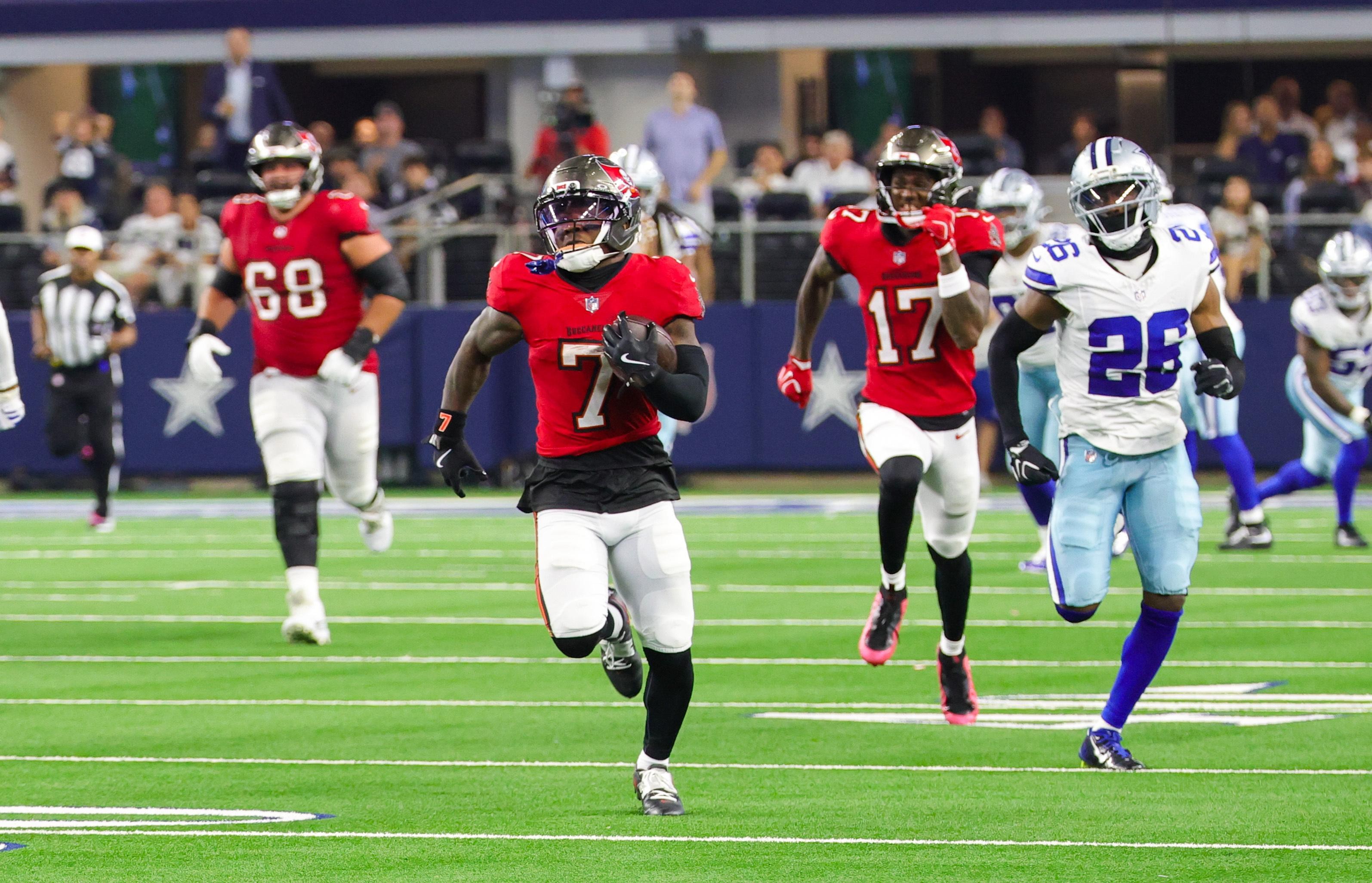 Bucky Irving corre com a bola contra a defesa dos Cowboys.