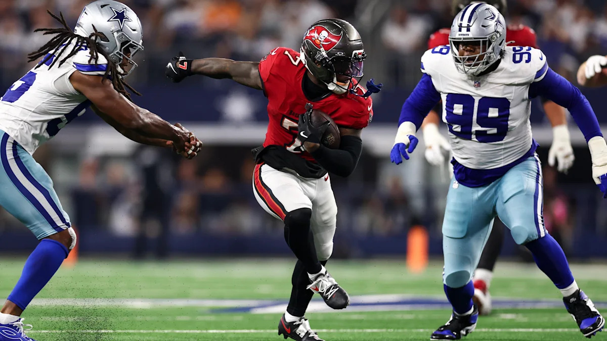Bucky Irving, do Tampa Bay Buccaneers, avança com a bola entre defensores do Dallas Cowboys.