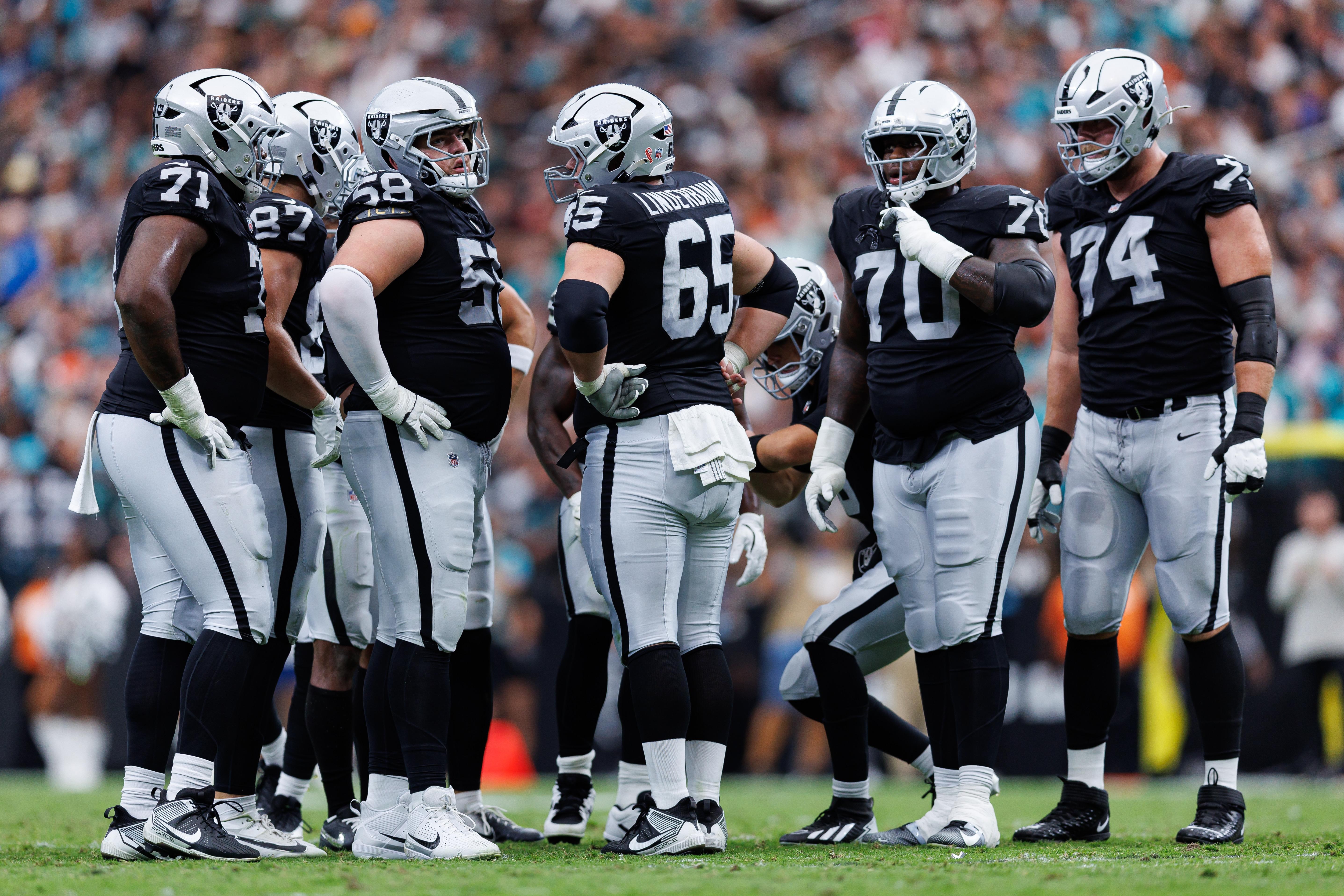 Jogadores da linha ofensiva dos Raiders se reúnem em campo.