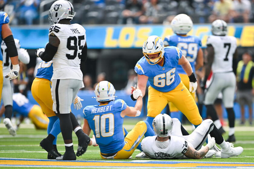 Jake Slaughter ajuda Justin Herbert a se levantar contra os Raiders, em 20 de setembro.