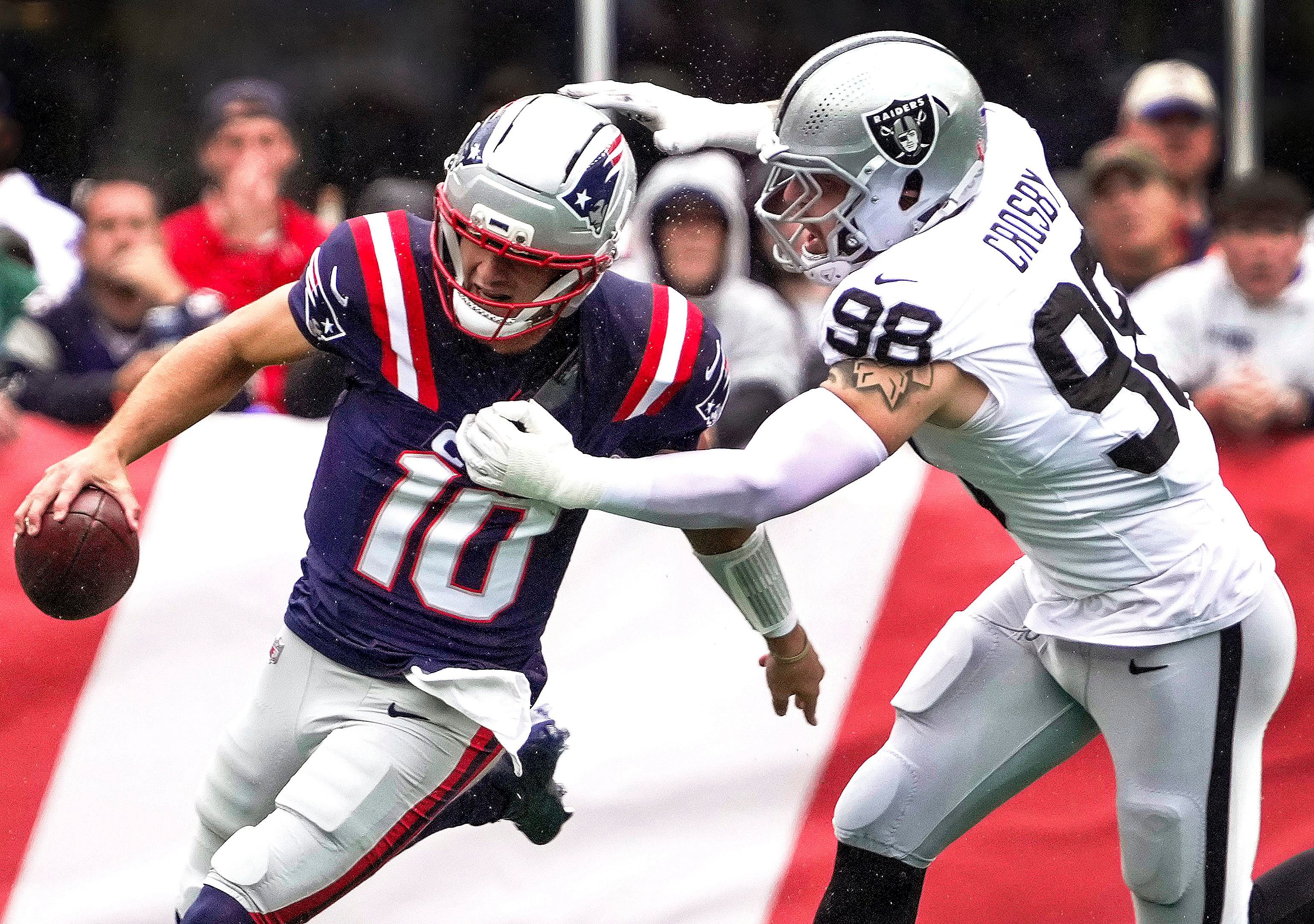 Jogadores de Patriots e Raiders disputam uma jogada.