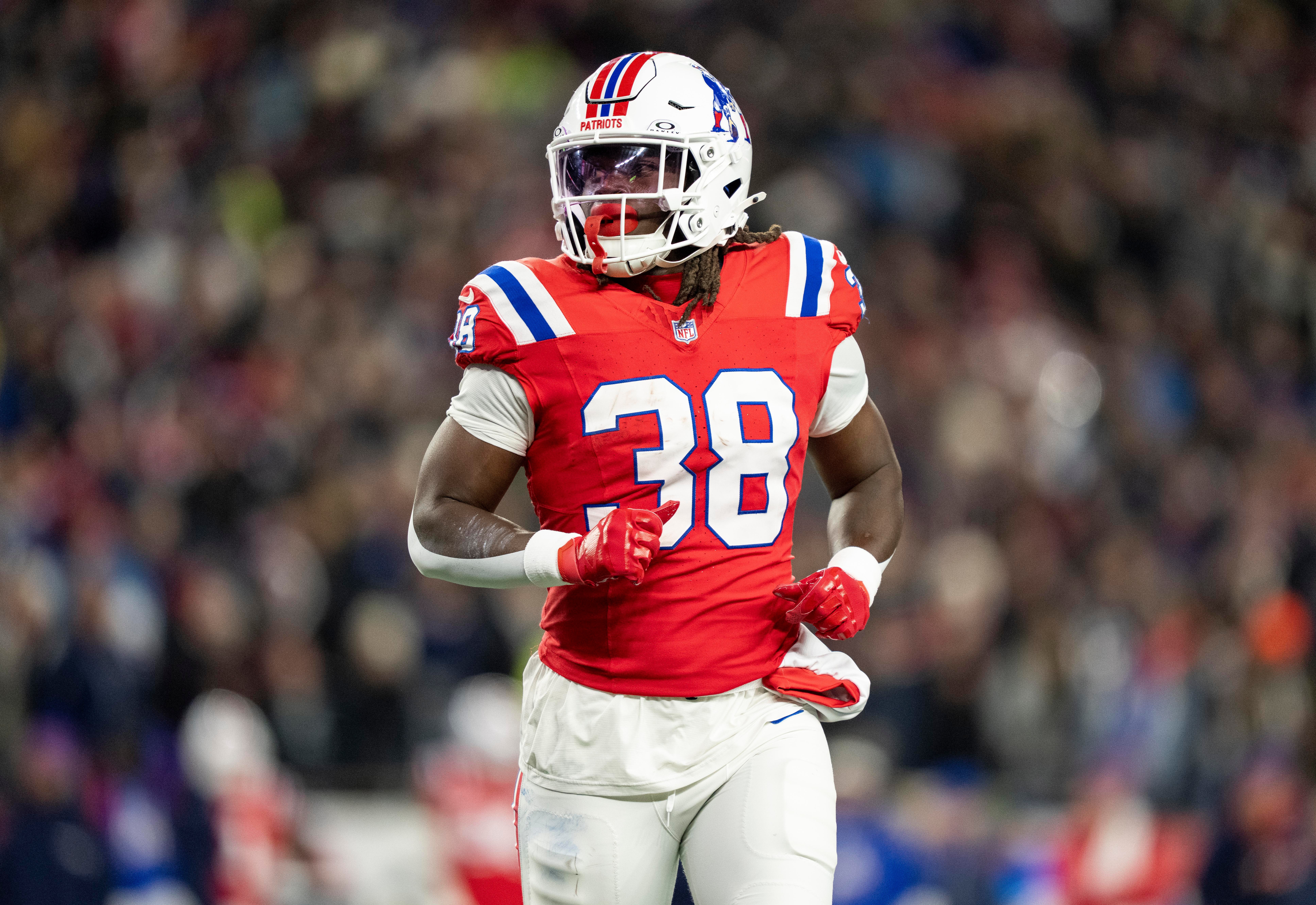 Rhamondre Stevenson corre com a bola pelo New England Patriots.