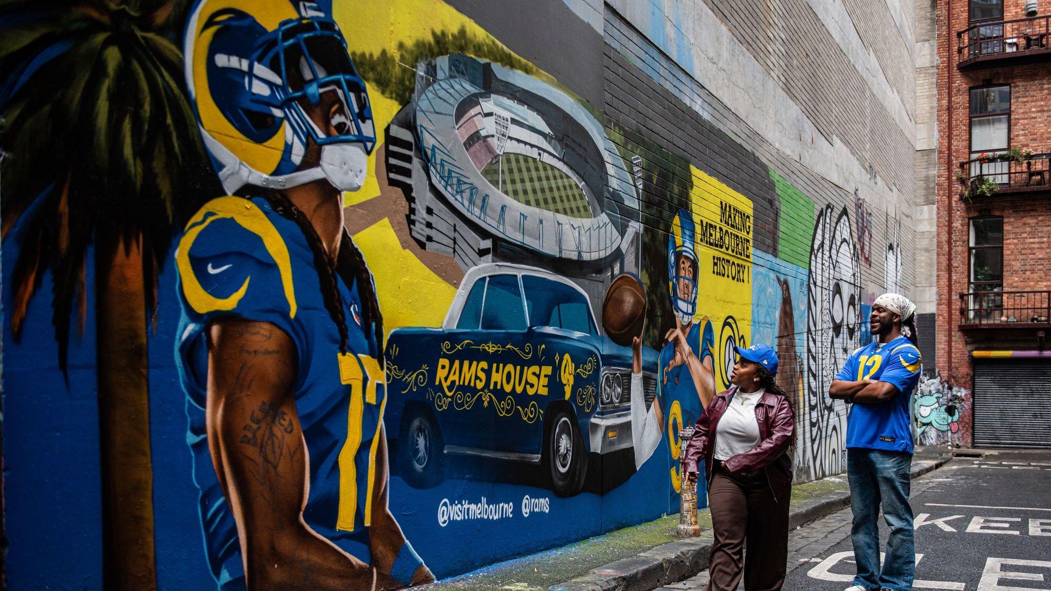 Torcedores dos Rams observam um mural da equipe em Melbourne