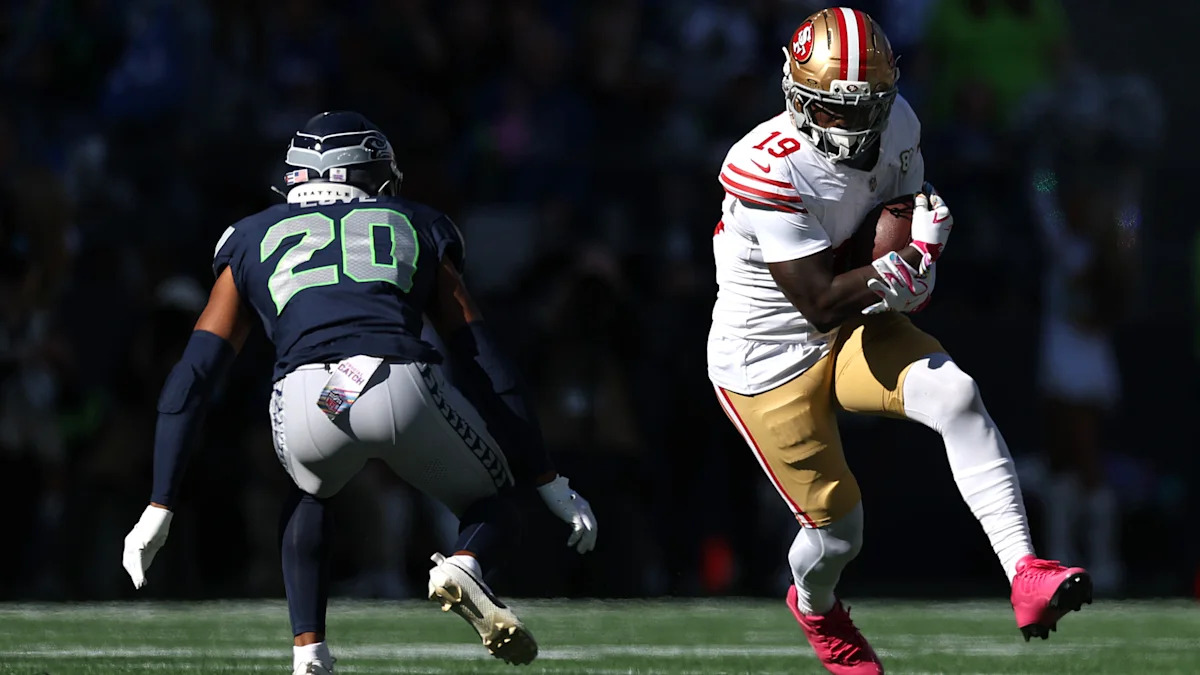 Deebo Samuel carrega a bola pelos 49ers diante de Julian Love, dos Seahawks.