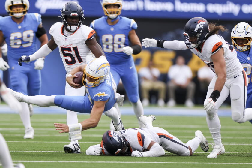 Justin Herbert é derrubado por Brandon Jones no confronto entre Chargers e Broncos.