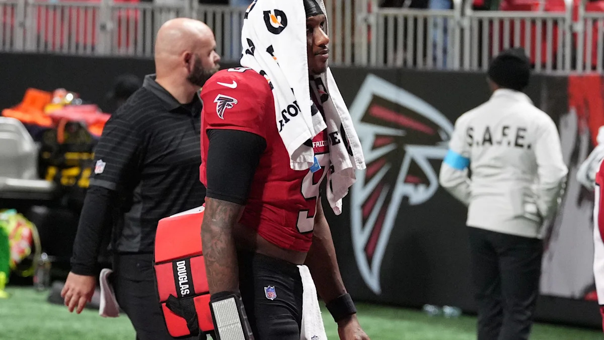 Michael Penix Jr. deixa o campo acompanhado por um profissional dos Falcons.