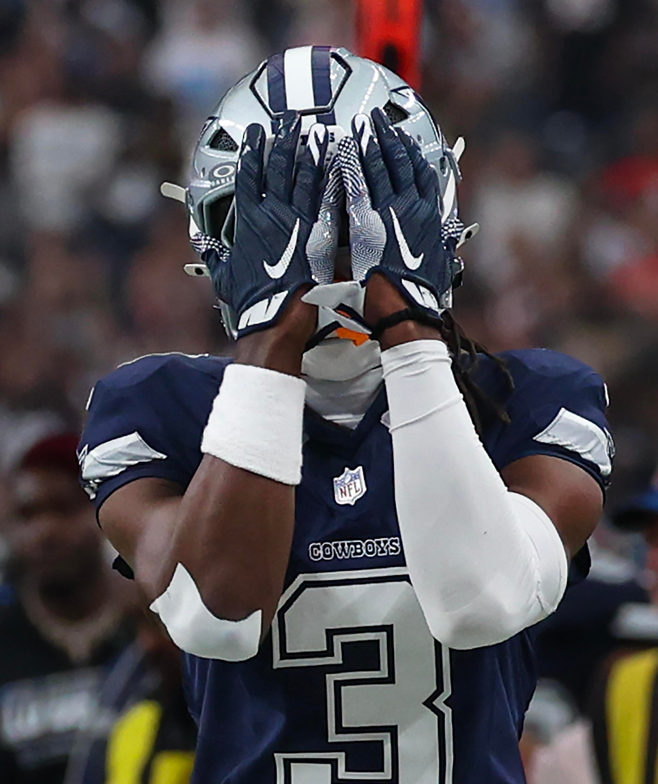 Jogador dos Dallas Cowboys cobre o rosto durante uma partida.