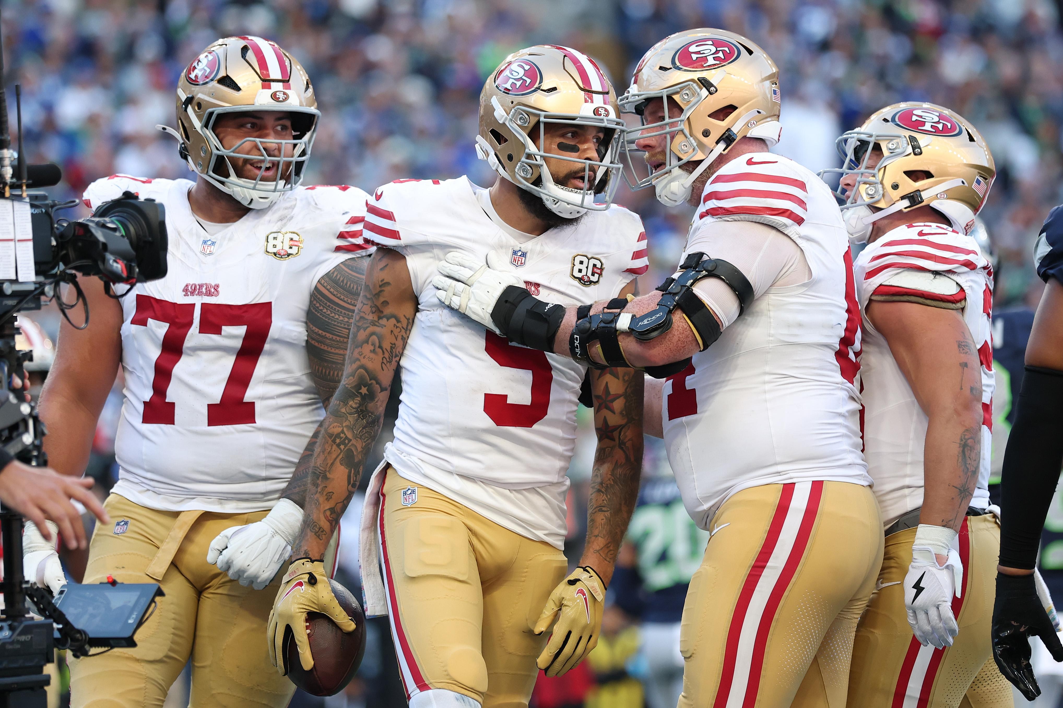 Jogadores dos 49ers se reúnem em campo durante partida em Seattle.