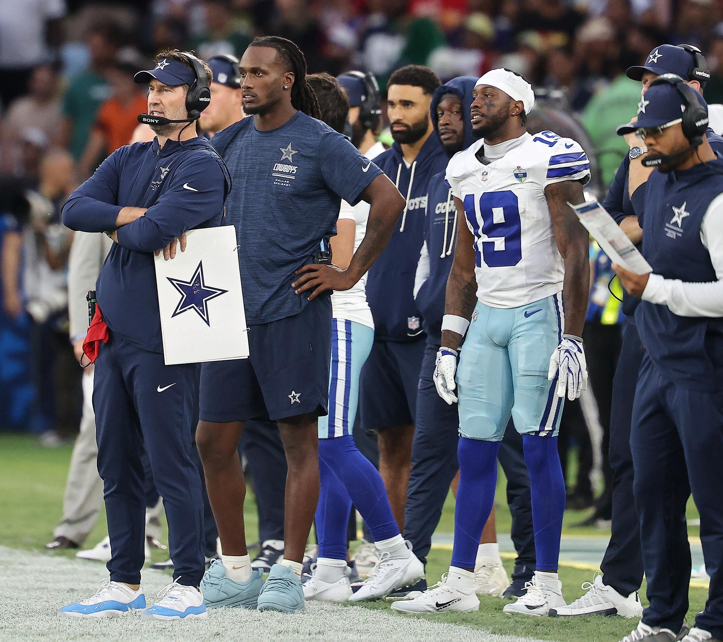 Integrantes da comissão técnica dos Cowboys acompanham uma partida.