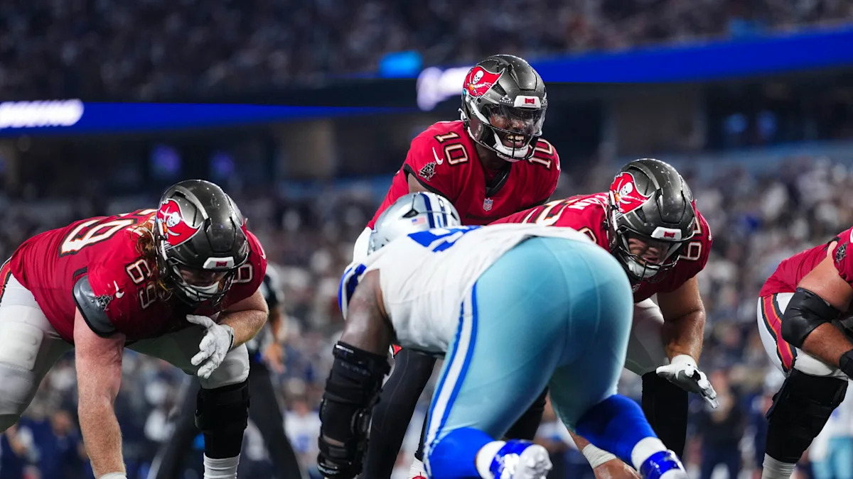 Jogadores dos Buccaneers e dos Cowboys se posicionam antes de uma jogada.