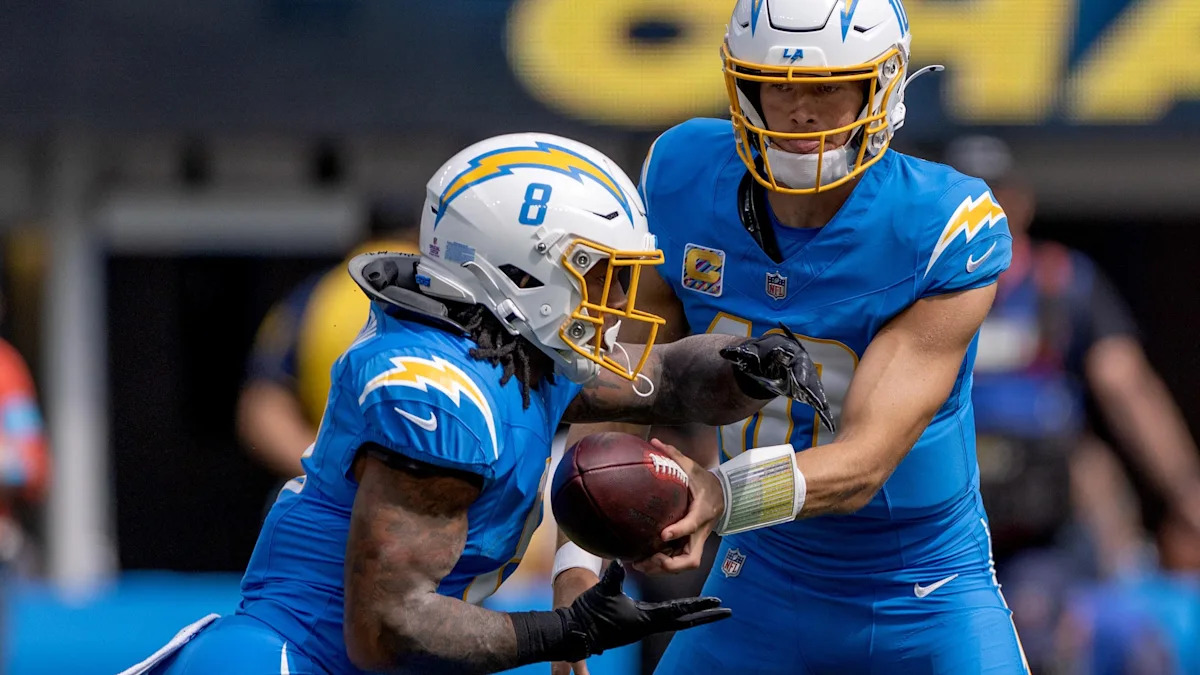 Justin Herbert entrega a bola a Omarion Hampton em uma jogada dos Chargers.
