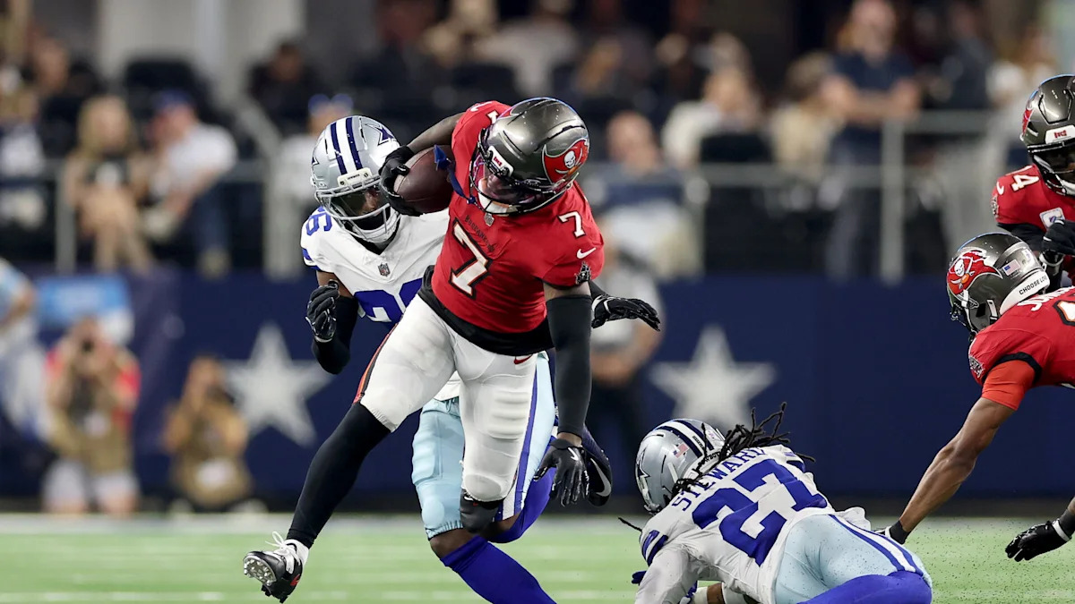 Bucky Irving enfrenta a defesa dos Cowboys com a bola.